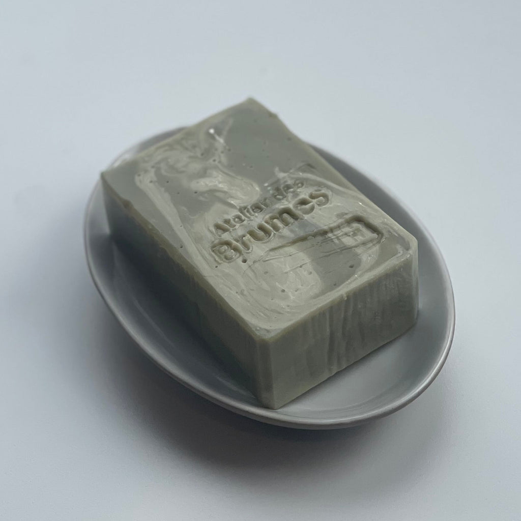 un savon vert sur un porte-savon ovale, sur fond blanc