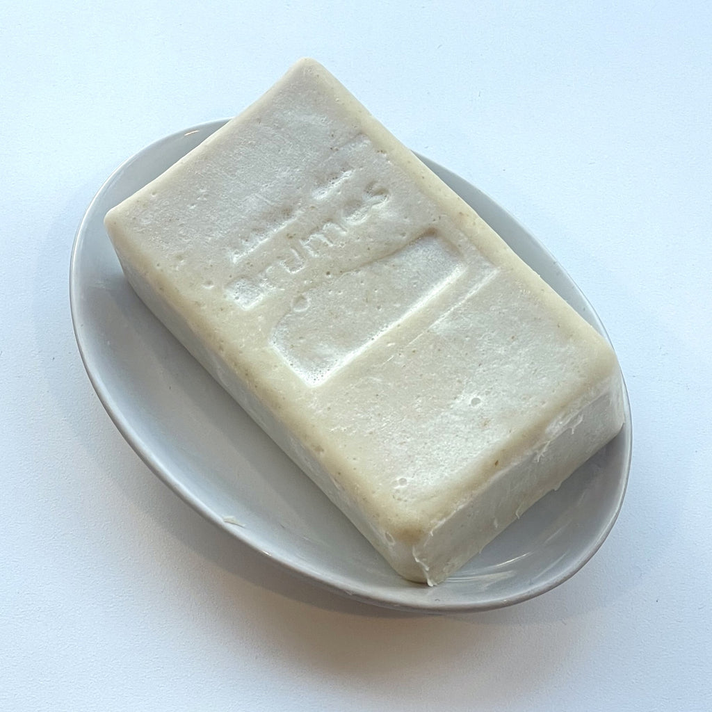 savon rectangulaire beige sur un porte-savon ovale sur fond blanc