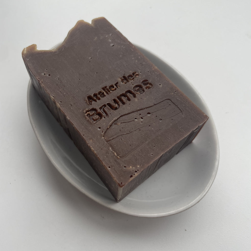 un savon rectangulaire brun sur un porte-savon oval