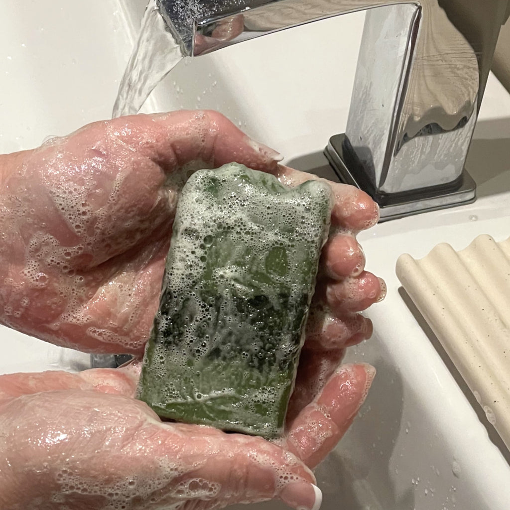 mains qui tiennent un savon vert couvert de mousse
