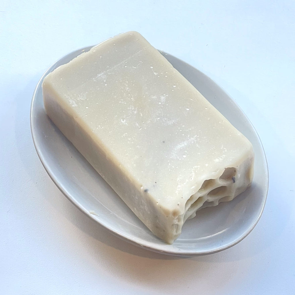 un savon rectangulaire avec un côté texturé sur porte-savon ovale